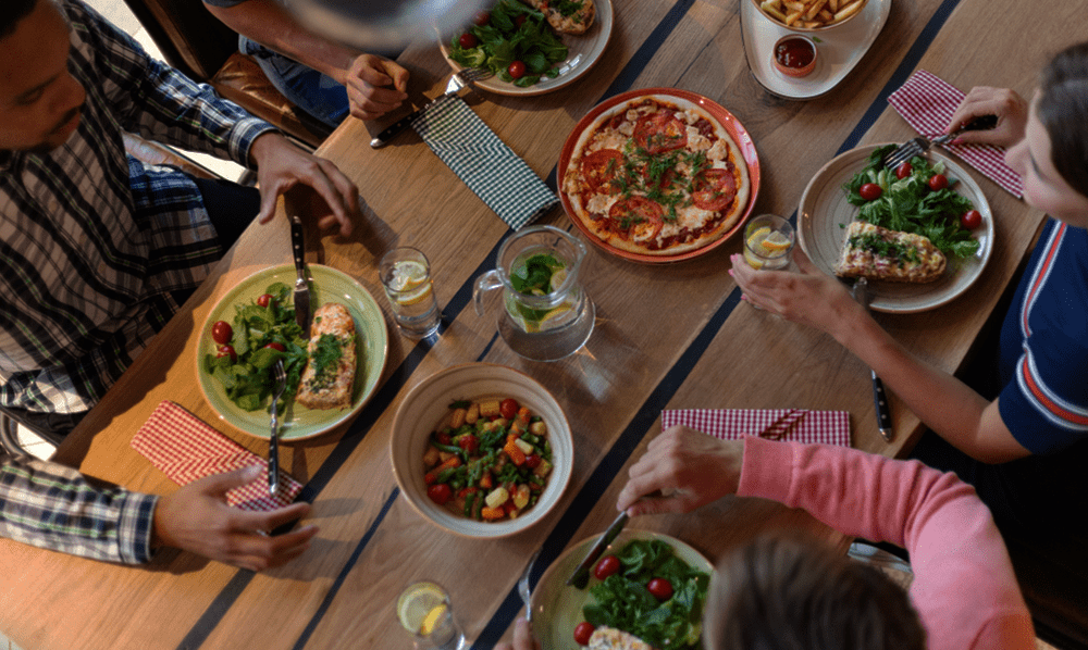 Pessoas sentadas à mesa comendo juntas